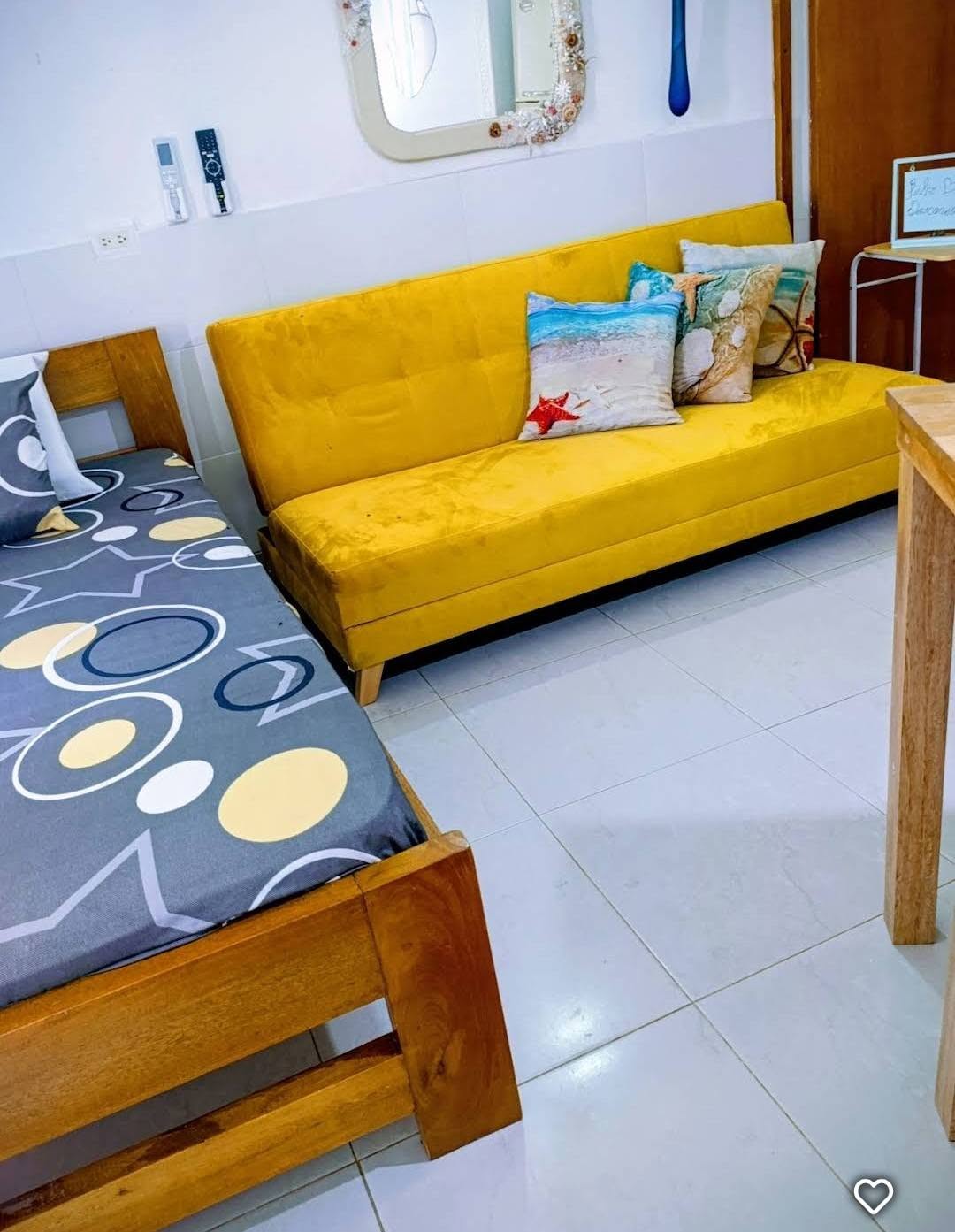 Sala con sofá amarillo y cama auxiliar